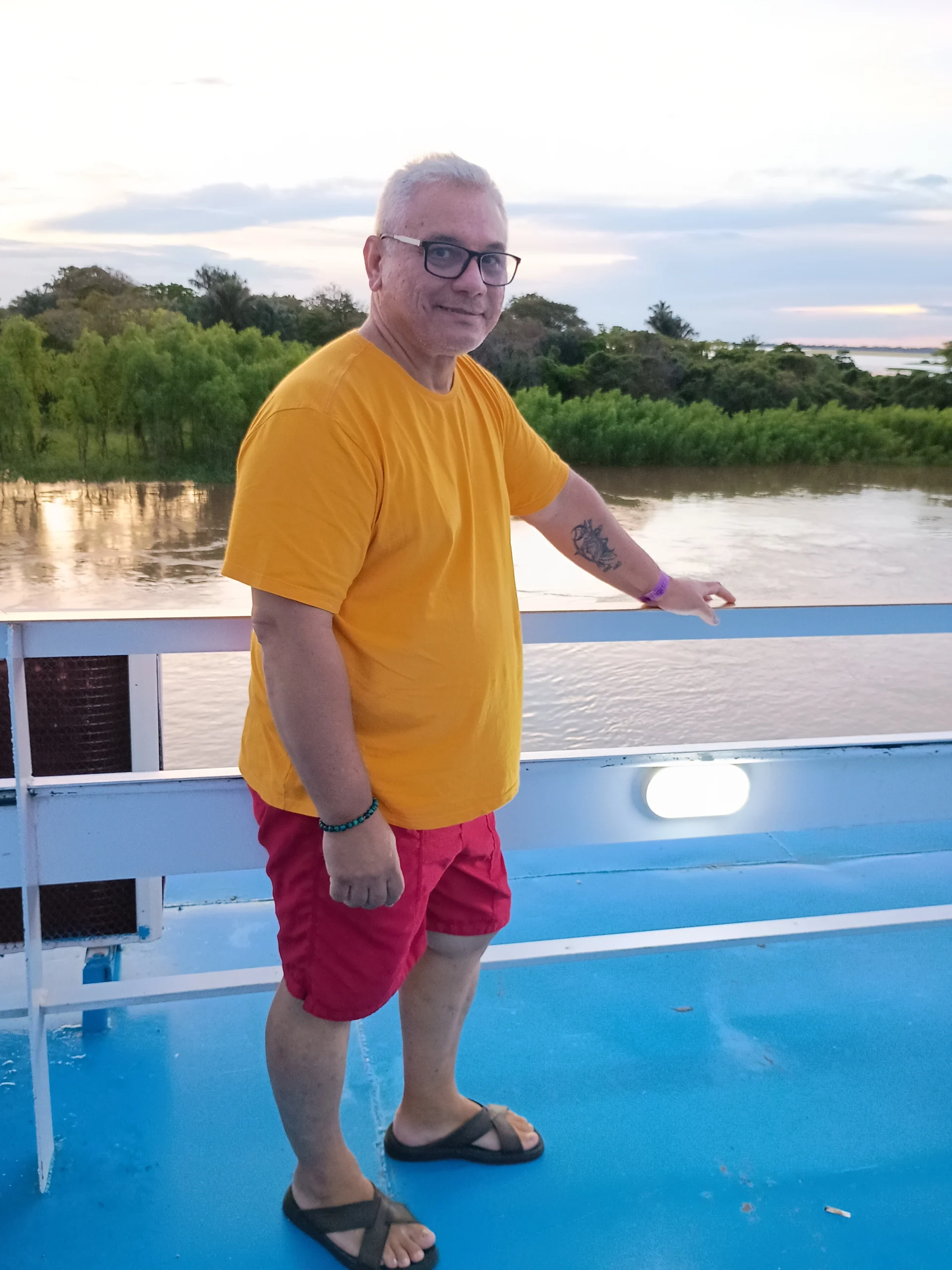 Alexandre Magno, criador do blog Conexão Lar, sorrindo de pé no convés de um barco com um grande rio ao fundo.